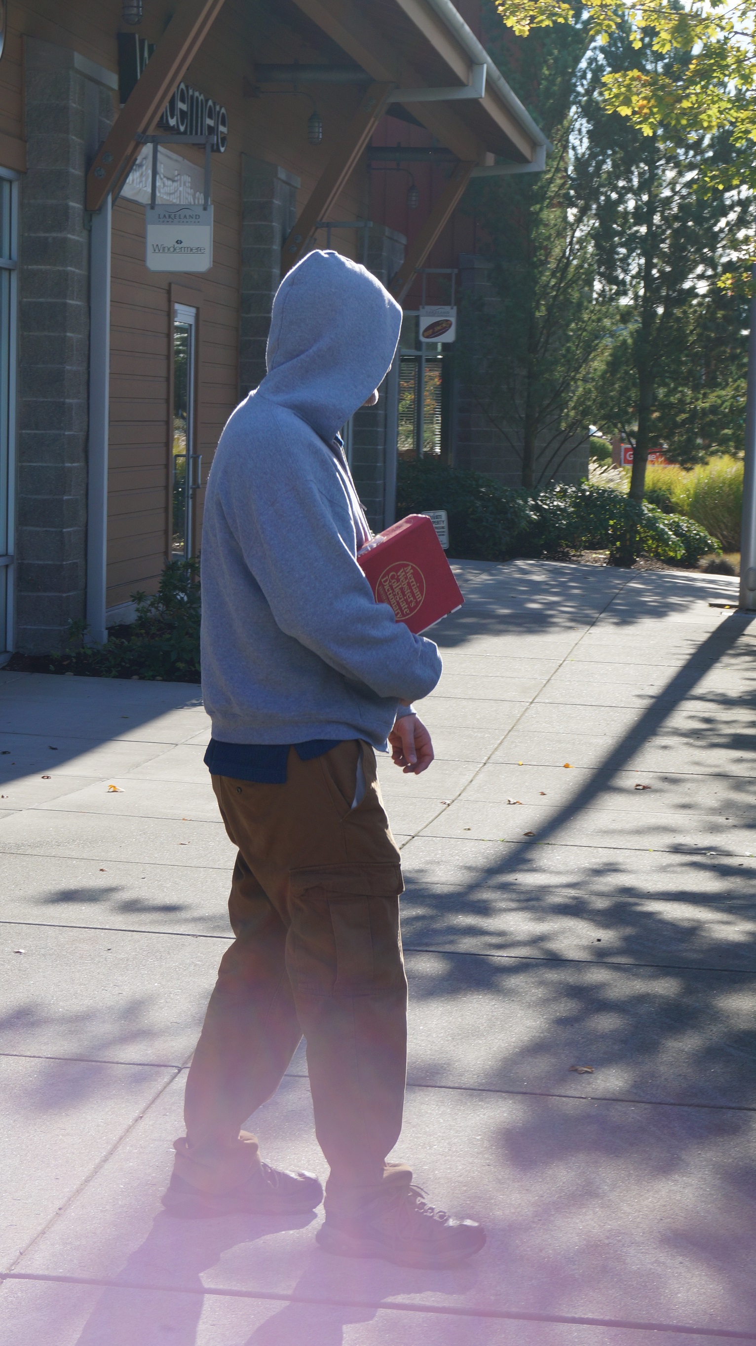 man carrying dictionary by some shops