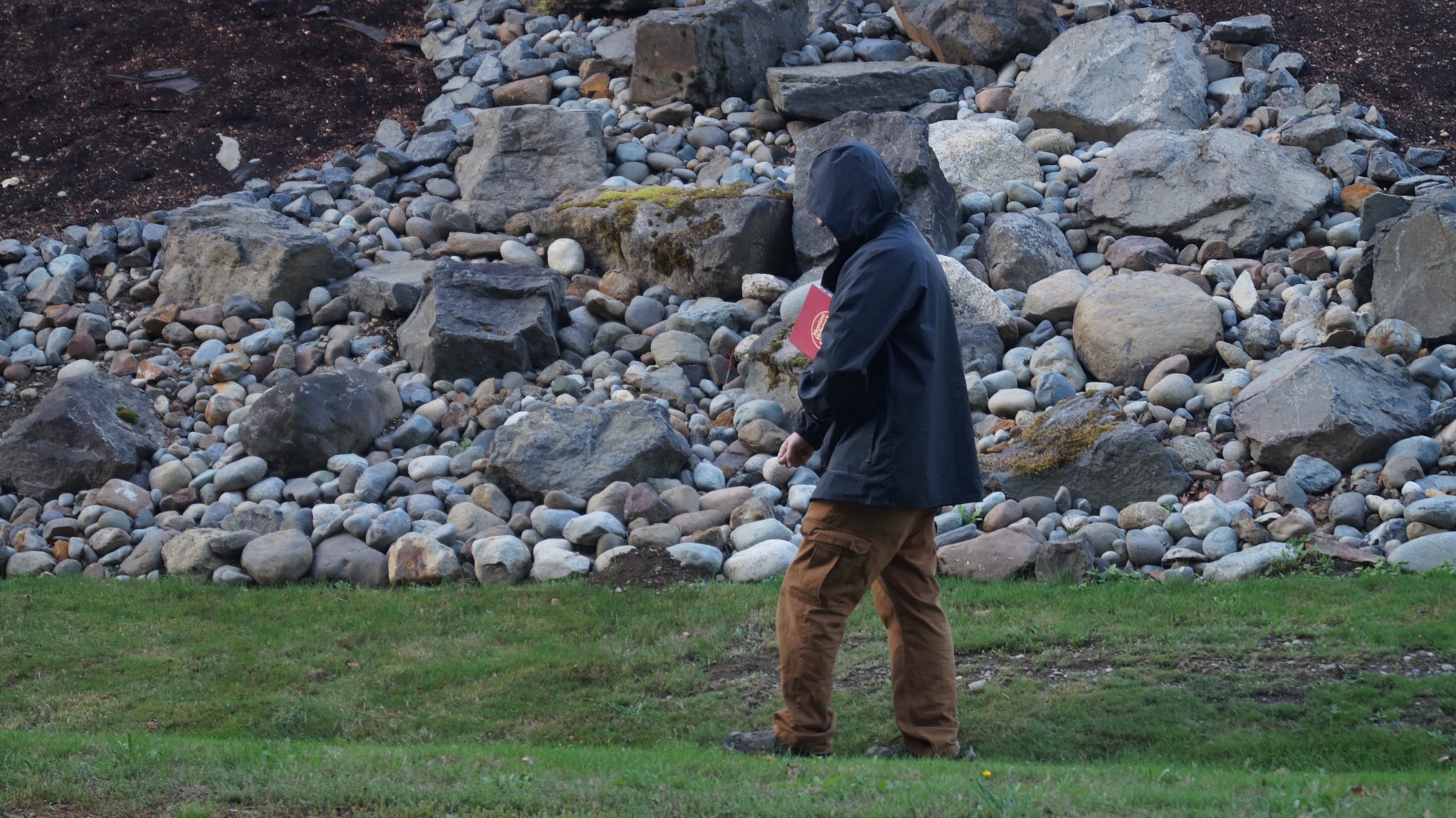 man with dictionary walking by rocks