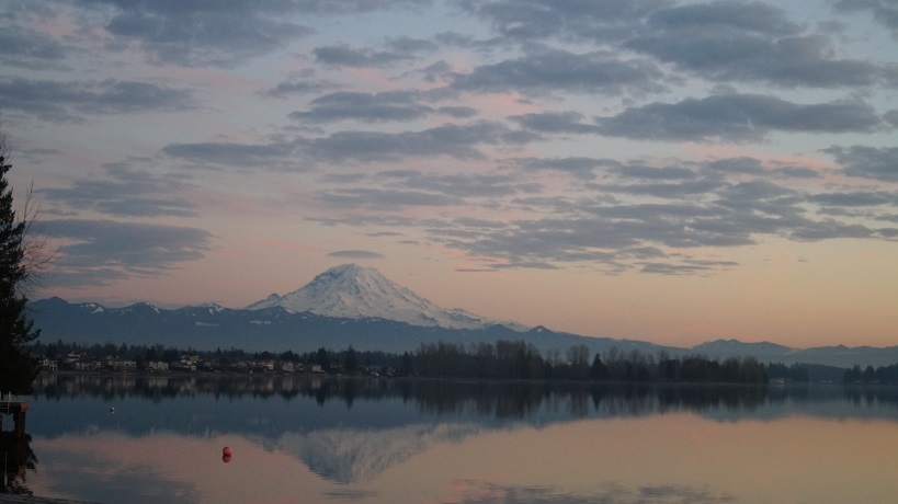 Mt. Rainier and its reflection in the lake in pastel hues at sunset.