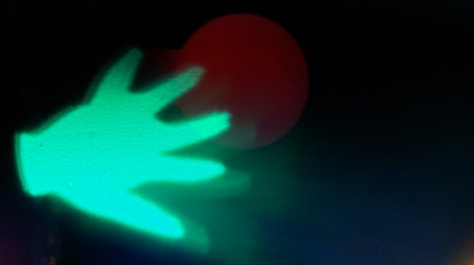 A glowing green hand in front of a burgundy circle. 