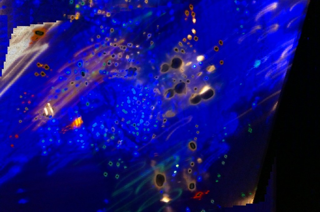 An abstract image featuring a blend of vibrant blue colors with scattered colorful dots and blurred patterns, creating an ethereal and dreamlike effect, with digital glitches at a diagonal along the left and right edges.