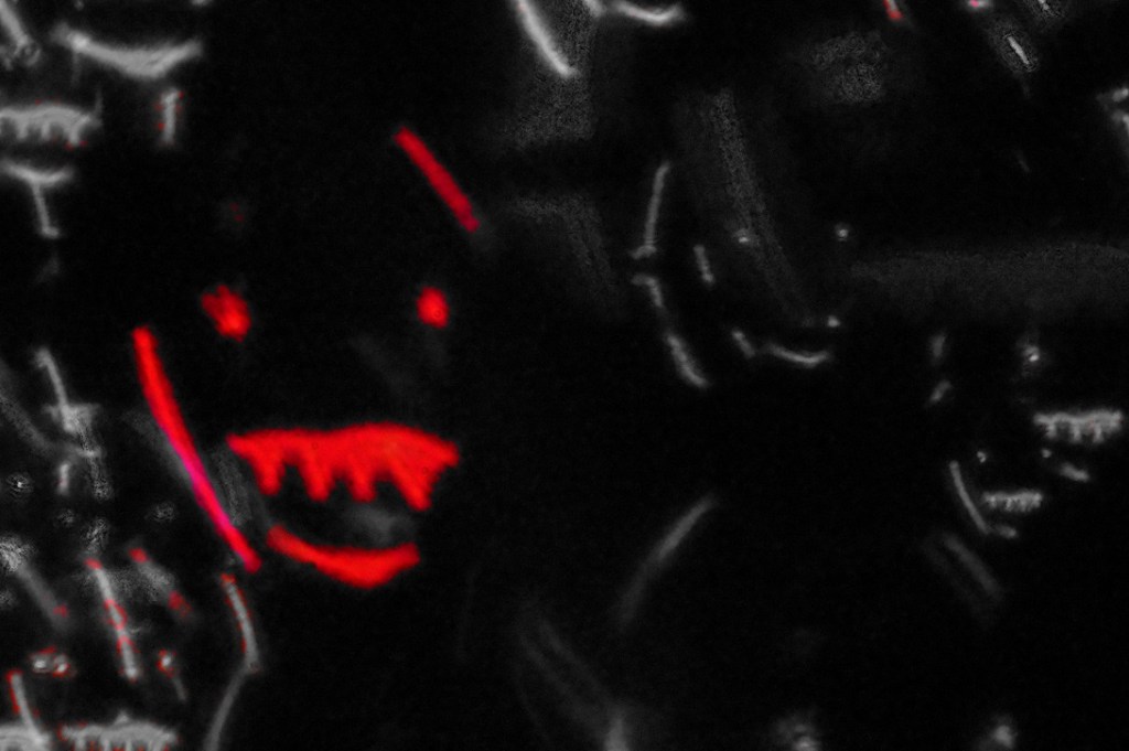 A dark and eerie abstract image featuring distorted shapes resembling monstrous faces with glowing red accents.